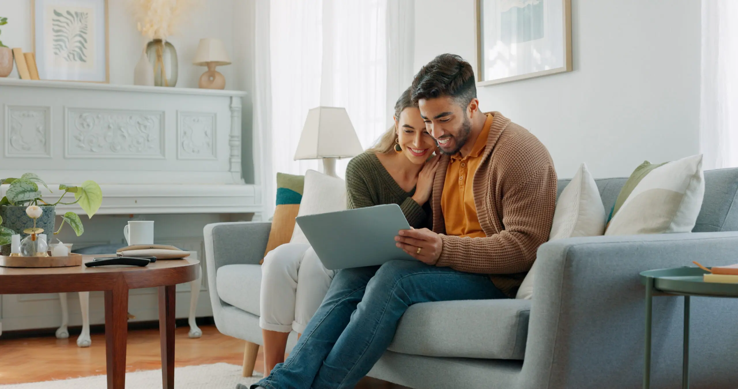 Laptop, living room and couple search website information for home investment, loan or real estate property discussion on sofa. Young people on couch with pc internet, planning future together