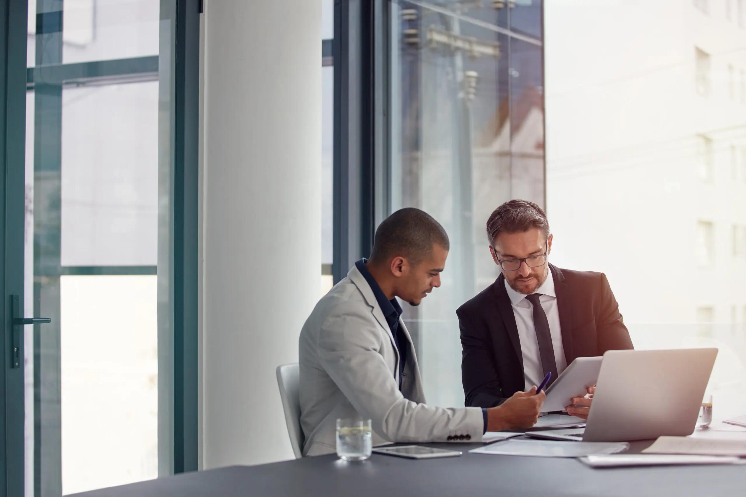 Tablet, laptop and business men planning in conference room meeting, teamwork and discussion of corporate data. Professional people or partner talking, review or report analysis on digital technology