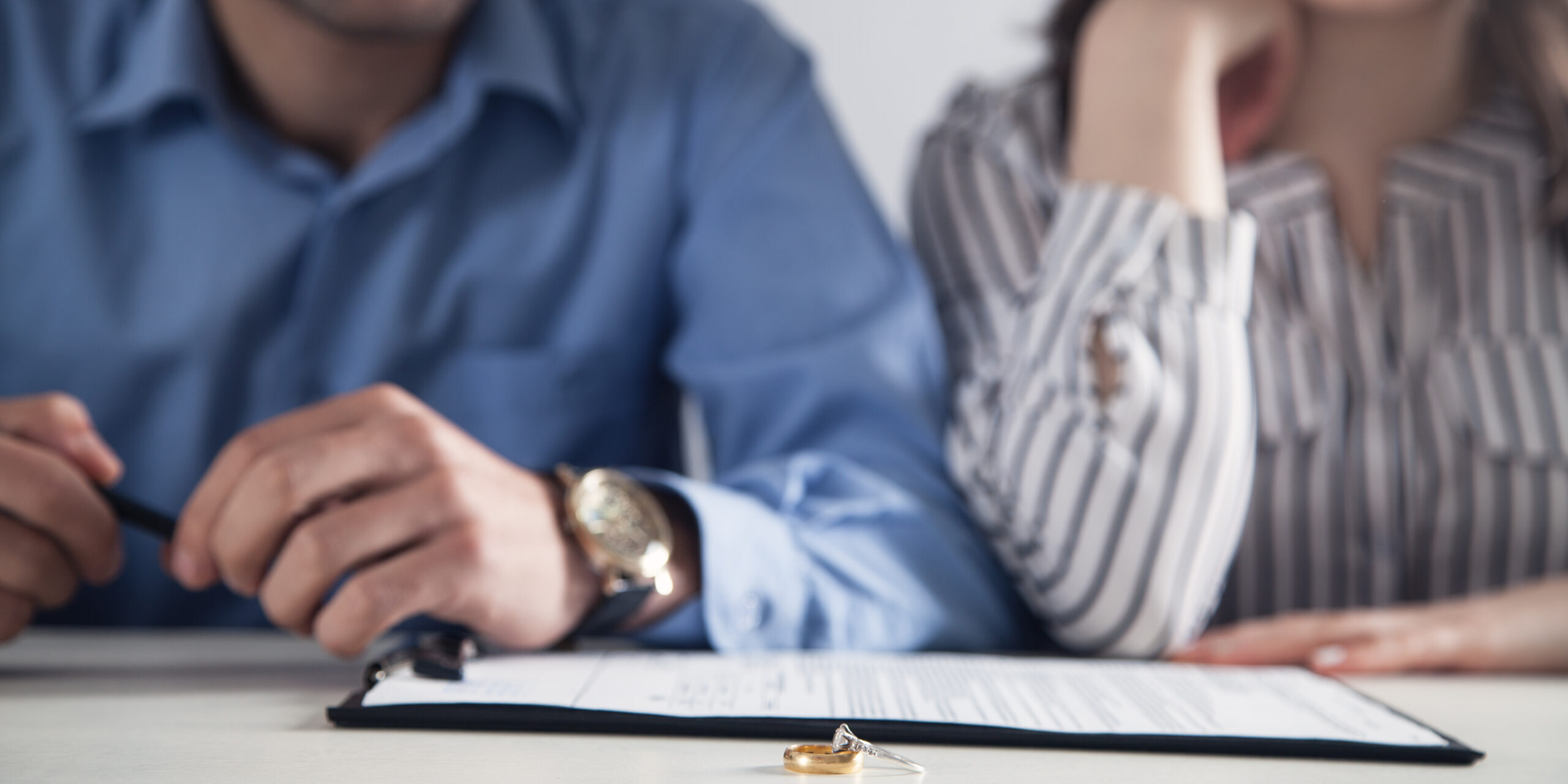 Couple with divorce contract and ring on desk. Divorce