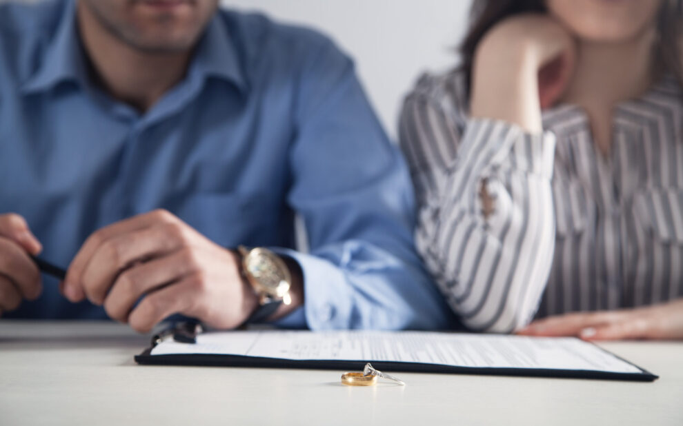 Couple with divorce contract and ring on desk. Divorce