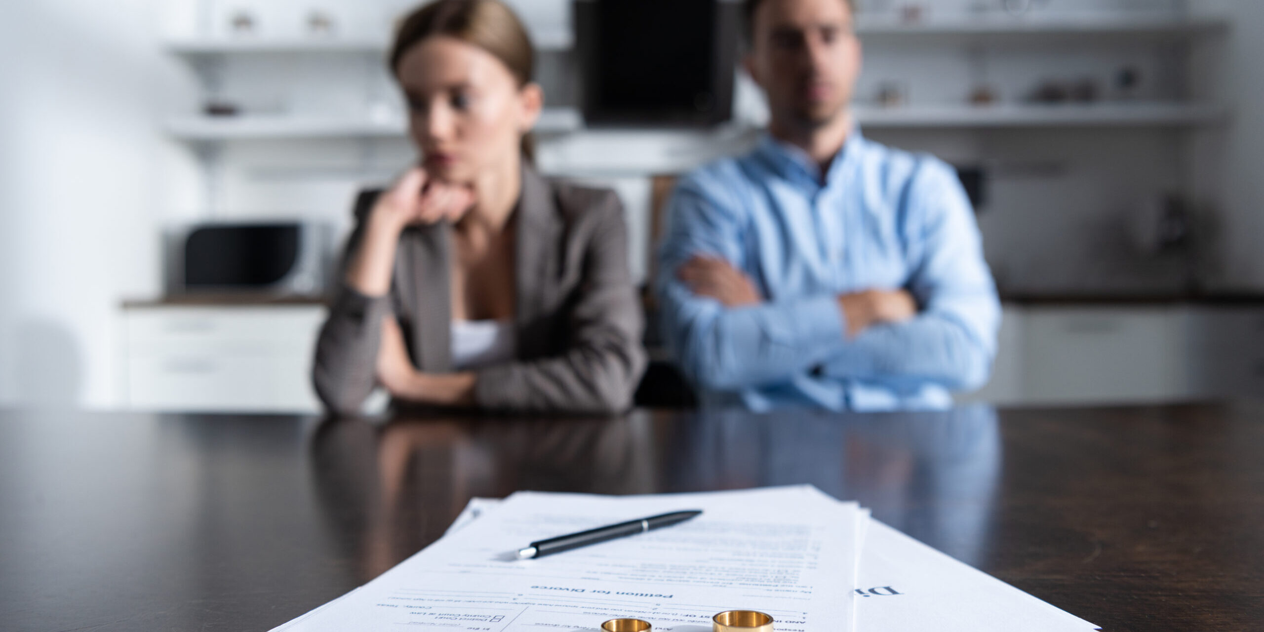 selective focus of couple sitting at table with divorce documents Insurance Following a Divorce