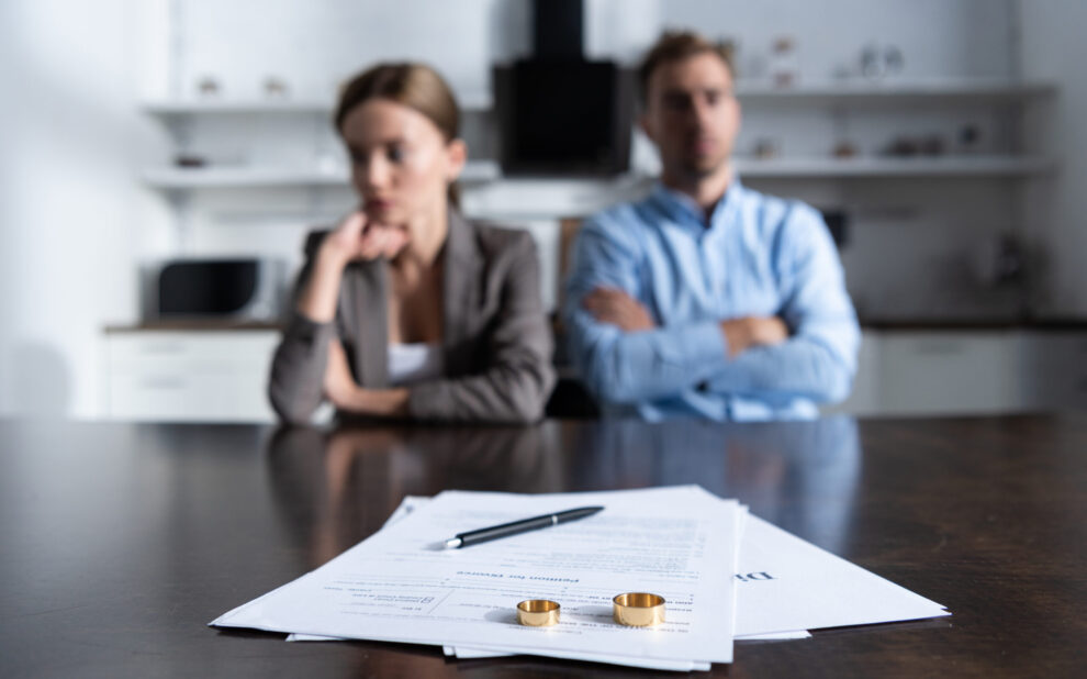 selective focus of couple sitting at table with divorce documents Insurance Following a Divorce