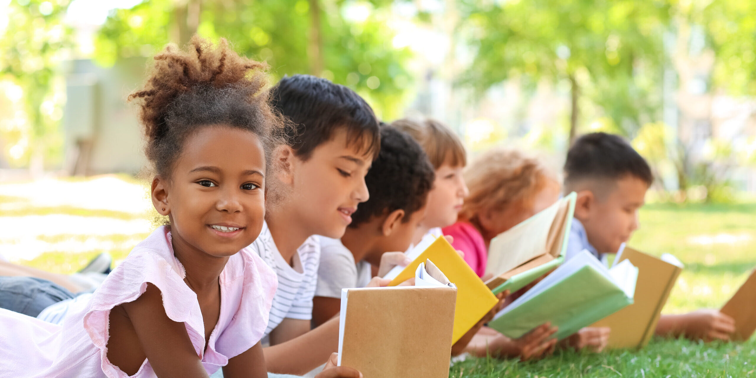 Cute little children reading books in park