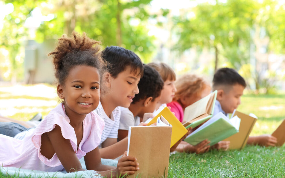 Cute little children reading books in park
