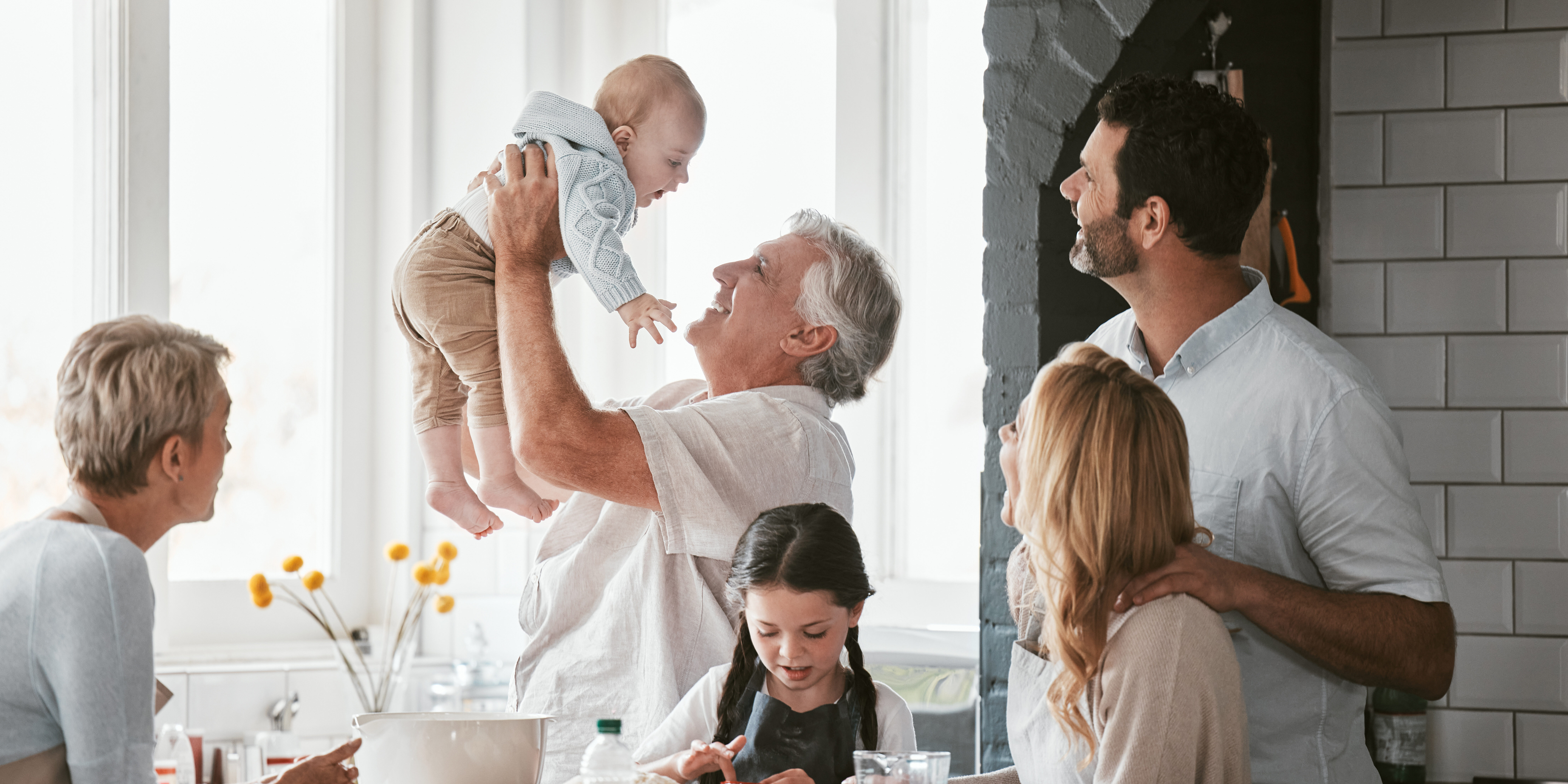 .Family, kitchen and grandpa playing with baby having fun, bonding and relax together. Big family, support or care of grandfather carrying newborn with mother, father and girl child cooking in house. inheritance tax planning