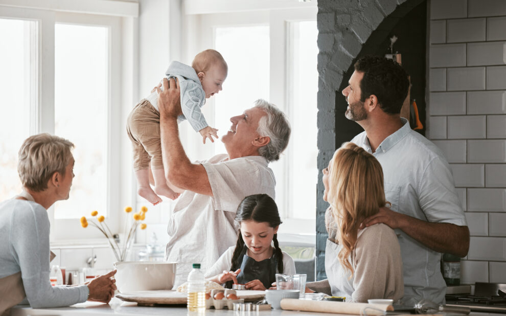 .Family, kitchen and grandpa playing with baby having fun, bonding and relax together. Big family, support or care of grandfather carrying newborn with mother, father and girl child cooking in house. inheritance tax planning