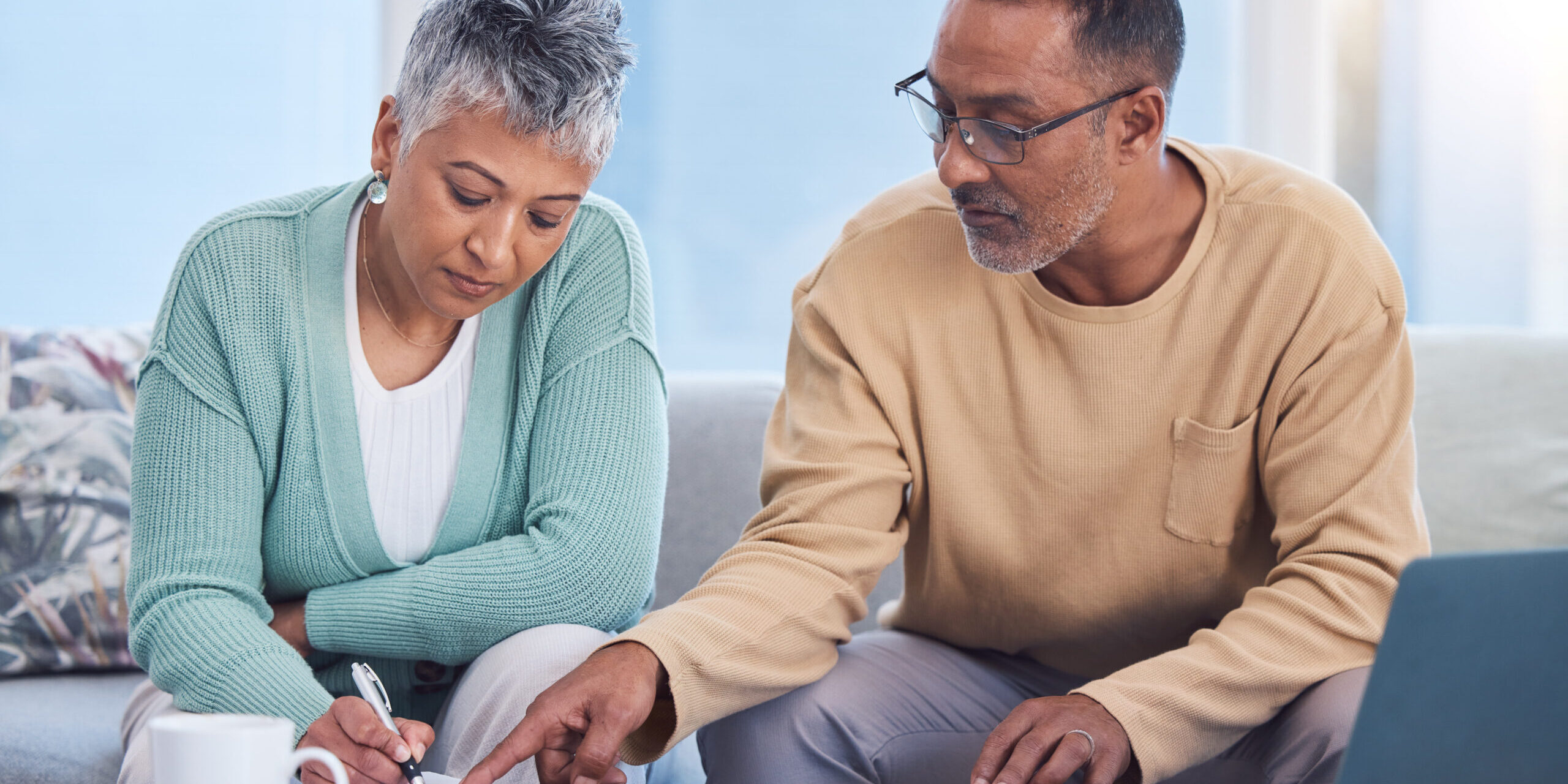 Senior black couple, taxes and home with laptop, documents or focus in home for family finance. Elderly, woman and man with computer, tablet or notebook in audit, budget or planning on lounge sofa taxes in retirement