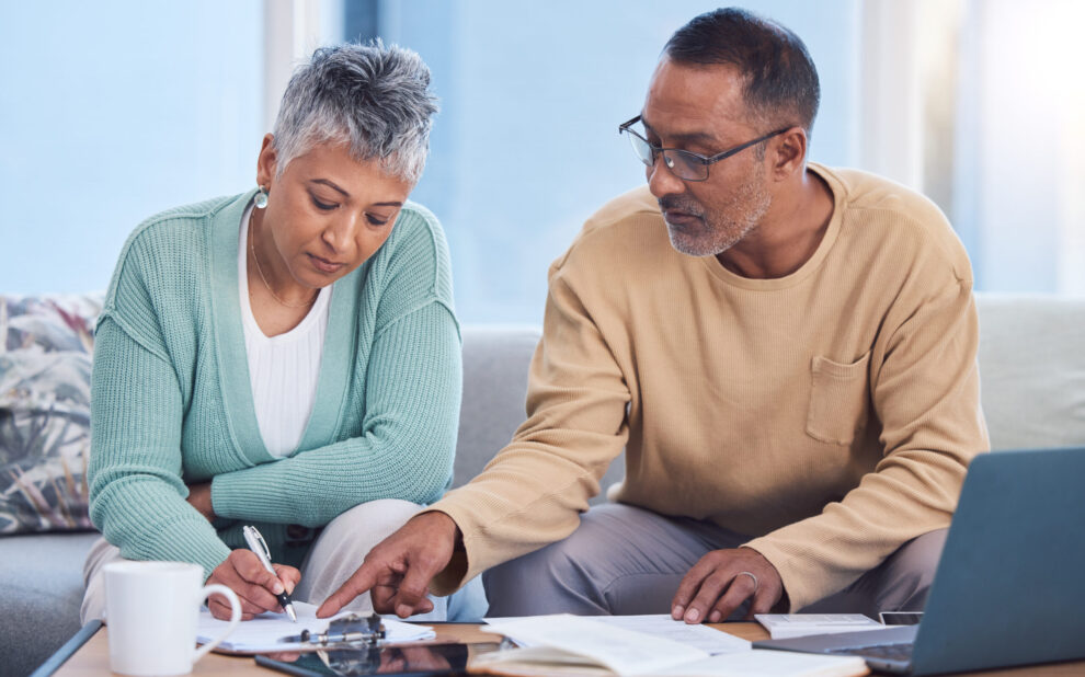 Senior black couple, taxes and home with laptop, documents or focus in home for family finance. Elderly, woman and man with computer, tablet or notebook in audit, budget or planning on lounge sofa taxes in retirement