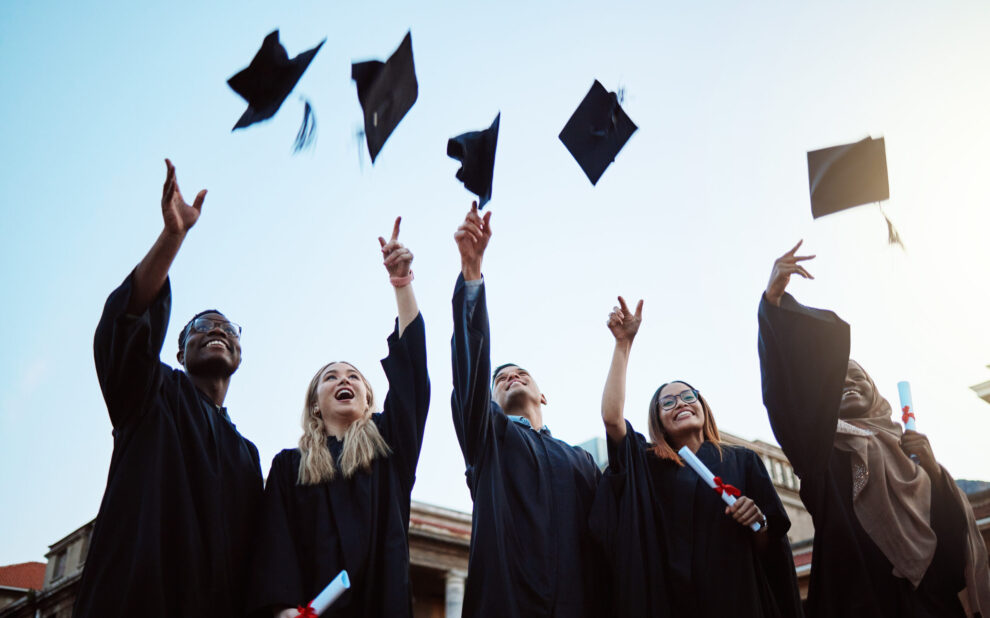 Graduation, education and success with friends in celebration as a graduate group outdoor, throwing mortar caps. Diversity, university and man and woman students celebrating a college diploma Cost of education College
