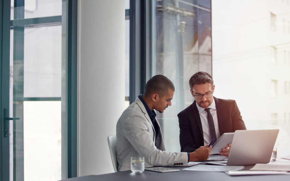 Tablet, laptop and business men planning in conference room meeting, teamwork and discussion of corporate data. Professional people or partner talking, review or report analysis on digital technology