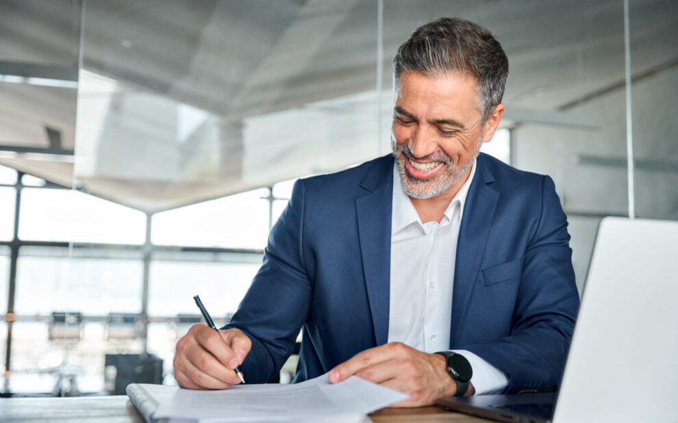 Happy satisfied middle aged professional business man signing documents. Business Owner Life Insurance