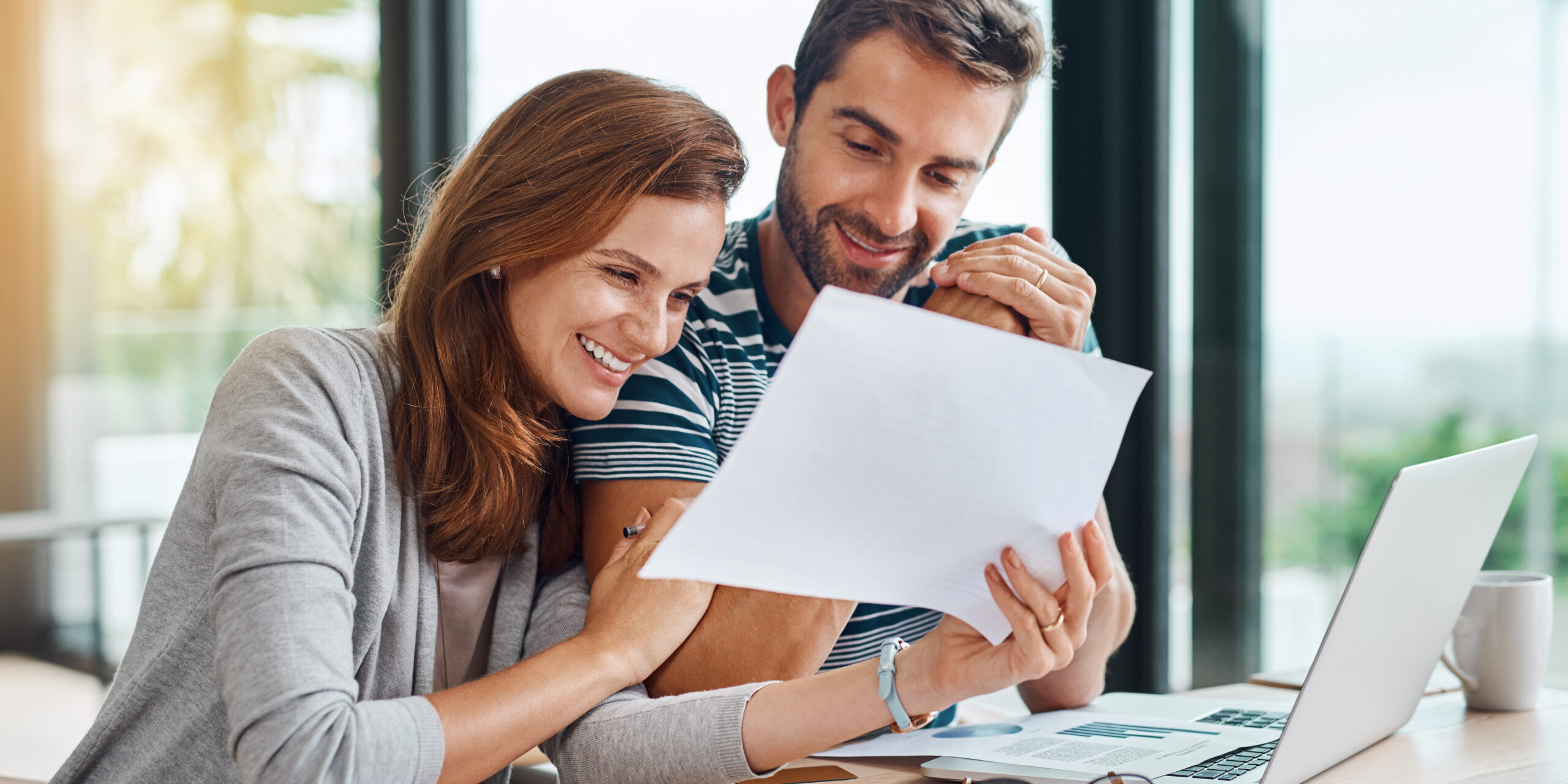 Documents, finance and couple planning budget for tax, bills and savings on laptop with banking, online payment and investment. People, paperwork and happy conversation on financial growth strategy