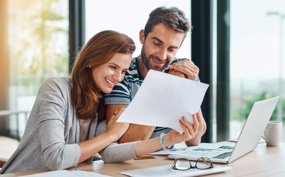 Documents, finance and couple planning budget for tax, bills and savings on laptop with banking, online payment and investment. People, paperwork and happy conversation on financial growth strategy