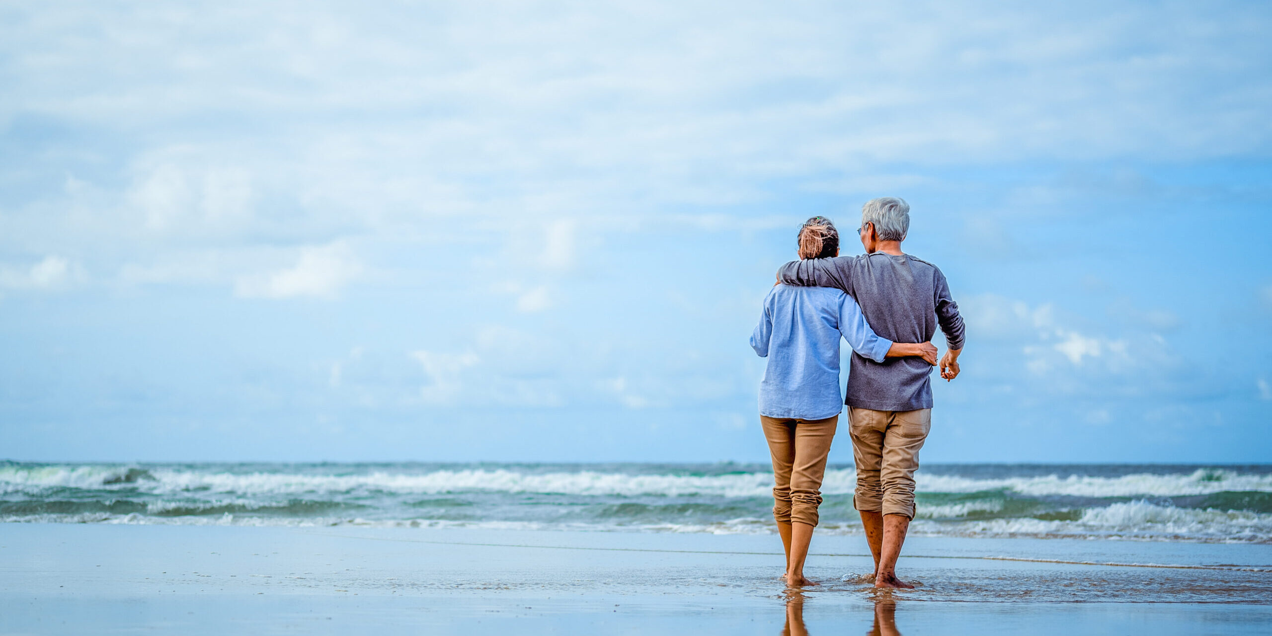 Senior couple walking on the beach holding hands at beach sunrise in evening. Retirement Withdrawal Strategies for Tax Efficiency