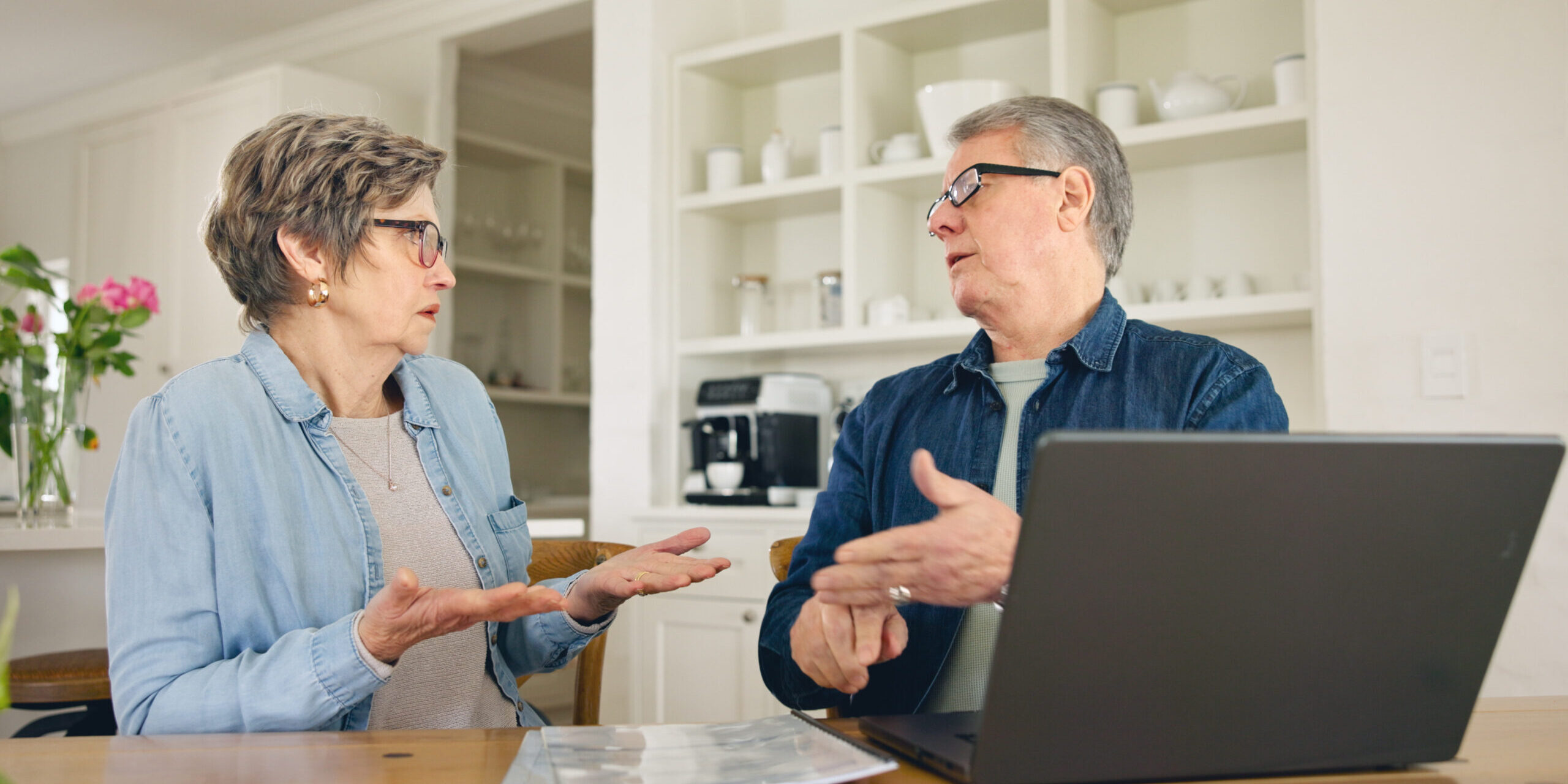 Laptop, budget and stress with a senior couple in their home together, talking about accounting or finance. Tax, debt or financial crisis with an elderly man and woman in disagreement about money