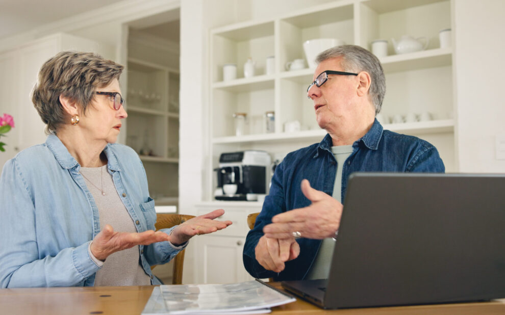 Laptop, budget and stress with a senior couple in their home together, talking about accounting or finance. Tax, debt or financial crisis with an elderly man and woman in disagreement about money
