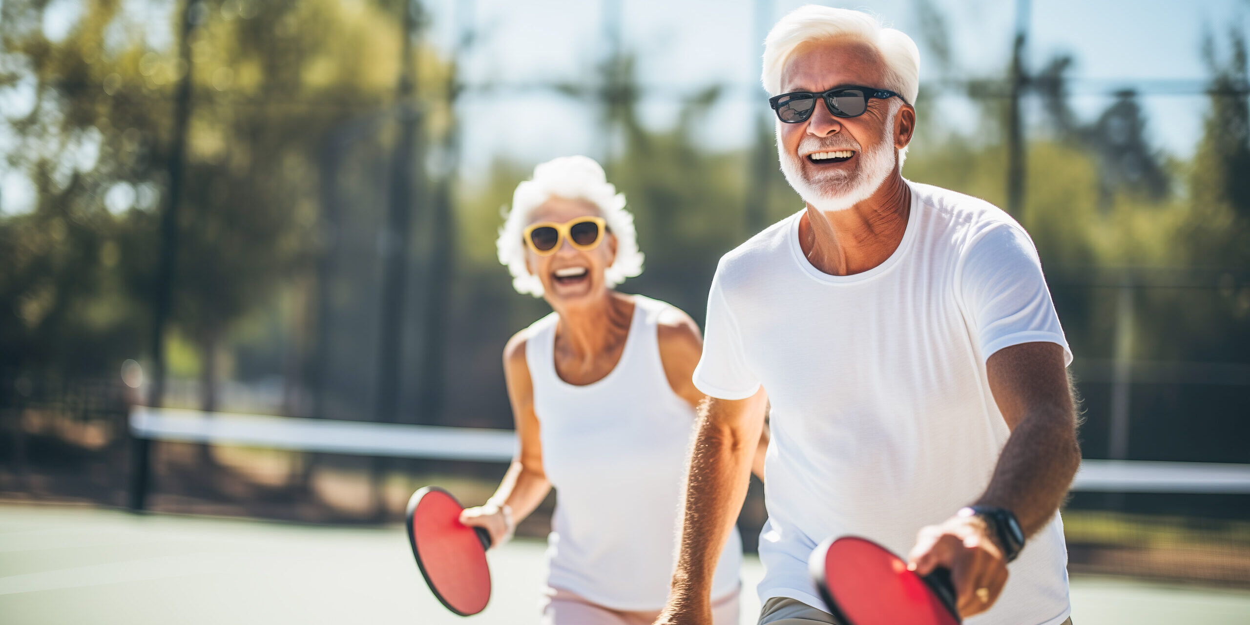 Couple of smiling seniors playing pickleball on a sunny day
